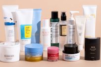 A variety of skincare products, including creams, balms, and serums, are arranged on a light surface. Products have different colored packaging and labels in various languages.